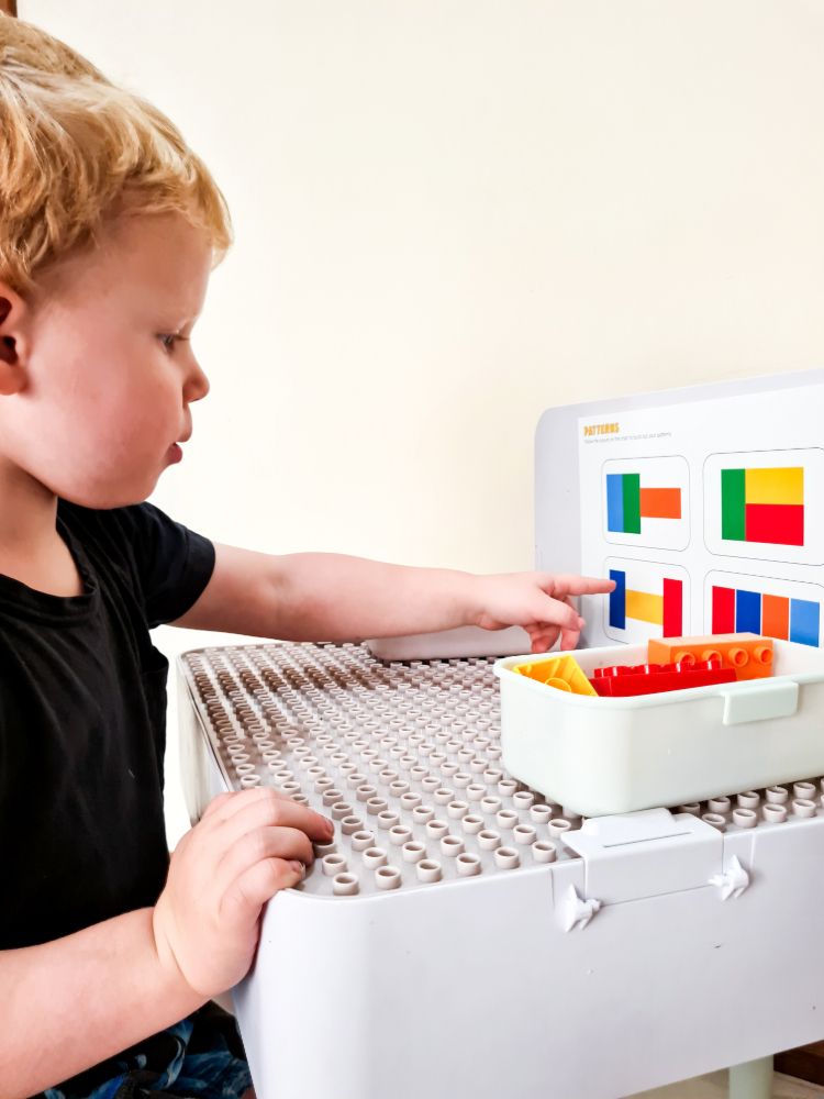A child following a colour pattern chart while building with bricks
